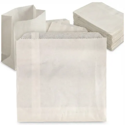 Plain white sulphite paper bags with serrated top edges: one flat bag in front, one standing open and a stack of flat bags behind, greaseproof bag, grease proof bag
